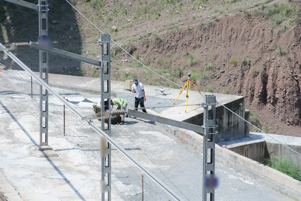 Two surveyors with a GNSS receiver and a survey drone on the ballastless track at Sangaldan